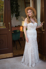  Beautiful slim blonde poses in boho wedding dresses and an embroidered corset on a summer terrace.