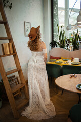  Beautiful slim blonde poses in boho wedding dresses and an embroidered corset on a summer terrace.