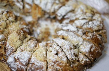 A closeup shot of a freshly baked, round pastry topped with powdered sugar and a crumbly streusel. 