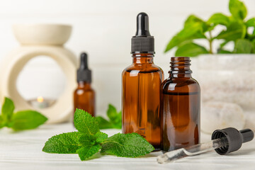 Essential oil mint on a wooden background. Peppermint essential oil with fresh mint leaves. A bottle of aromatherapy oil. Mint extract. The concept of natural cosmetics, spa care. copy space