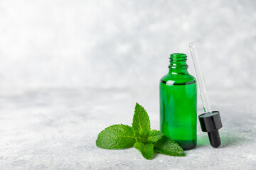 Essential oil mint on a wooden background. Peppermint essential oil with fresh mint leaves. A bottle of aromatherapy oil. Mint extract. The concept of natural cosmetics, spa care. copy space