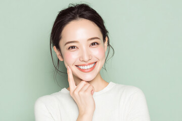 笑顔できらめく綺麗な肌と白い歯を見せる日本人女性美人モデルの接写写真。オーラルケア、スキンケア、コスメ広告用。