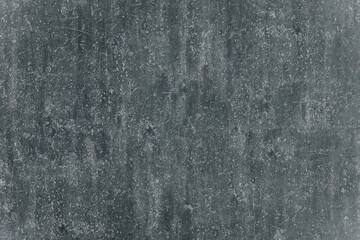 Close-up of a weathered, dark gray concrete wall with a gritty texture and subtle, worn markings