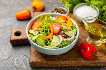 Cucumber salad on a wooden background.Homemade salad with fresh vegetables, cucumber, tomato, sweet pepper and lettuce in a plate.Vegetarian spring salad.Vegetarian diet.Healthy eating.Space for text