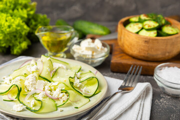 Cucumber salad on a wooden background.Homemade salad with fresh vegetables, cucumber, tomato, sweet pepper and lettuce in a plate.Vegetarian spring salad.Vegetarian diet.Healthy eating.Space for text