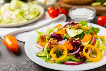Cucumber salad on a wooden background.Homemade salad with fresh vegetables, cucumber, tomato, sweet pepper and lettuce in a plate.Vegetarian spring salad.Vegetarian diet.Healthy eating.Space for text