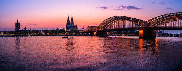 Obraz premium Evening silhouette skyline landscape of the gothic Cologne Cathedral, Hohenzollern railway and bridge, the old town and Great St Martin church in Cologne, Germany after sunset into blue hour