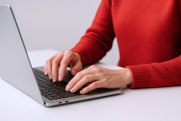 Naklejka premium Woman typing on laptop, close-up of hands on keyboard, working from home, remote office