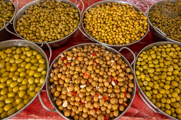 Trays with marinated black green yellow olives at farmers market close-up