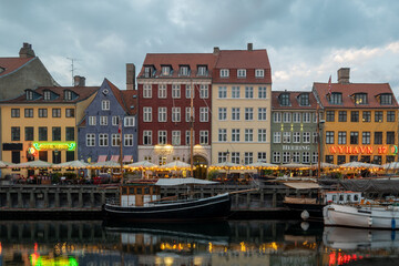 The iconic, colorful houses of Nyhavn, Copenhagen, reflected in the canal. The picturesque scene with boats moored along the banks is a famous symbol of Danish tourism and culture.
