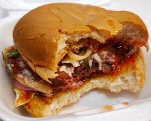 Savoring the deliciousness of a classic street burger!  Served in a handy styrofoam container, it's the perfect on-the-go meal. Whether you're indulging in a juicy cheeseburger.