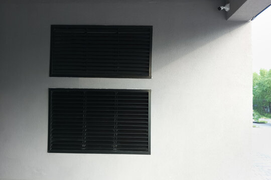 Black ventilation grille and surveillance camera on the grey wall of a building. - Powered by Adobe