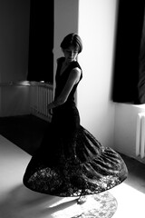 Elegant woman in sophisticated black gown captures graceful movement in contemporary concrete...