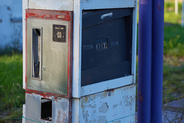 Rusty vintage fuel dispenser with metal casing and mechanical dials, peeling paint. For historical, industrial, automotive game design. Mechanical components indicate mid-20th-century retro technology