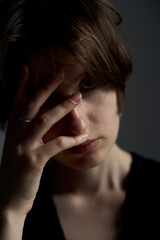 Professional portrait of brunette woman in black sleeveless dress with hand covering part of face in elegant pose