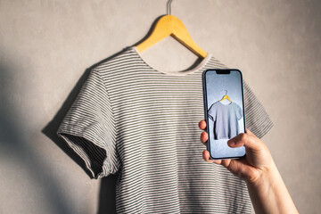 Close up of hands holding smartphone camera capturing old clothes items for online resale resources. Image for second hand concept.