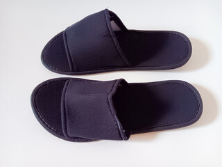 Pair of black disposable hotel guest slippers isolated on white background.	