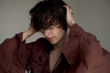 Young man in burgundy blazer with hand on forehead in stressed contemplative studio portrait