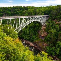 High-arched bridge spanning a lush green valley with a river below