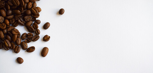 Coffee beans scattered on a clean white surface, showcasing their rich brown color and texture, creating a visually appealing composition with ample copy space for design purposes