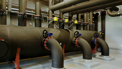 Industrial pipes and valves connecting to large tanks in a processing facility