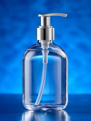 Clear soap dispenser on a blue background.