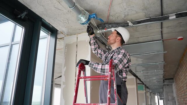 Plumber working on fire protection pipes in building under construction