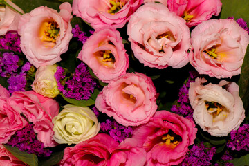 Bright and delicate bouquet of fresh flowers — pink and white lisianthus combined with purple statice, wrapped in yellow craft paper. Close-up, horizontal composition, isolated on a light background. 