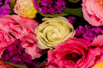 Bright and delicate bouquet of fresh flowers — pink and white lisianthus combined with purple statice, wrapped in yellow craft paper. Close-up, horizontal composition, isolated on a light background. 