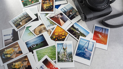 Polaroid photographs spread out on a table beside a camera capturing memories from various outdoor...