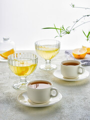 Variety of tea and citrus drinks displayed in elegant glassware on a light surface