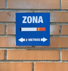 Letrero aviso de zona de fumadores en una pared de ladrillo en una calle 