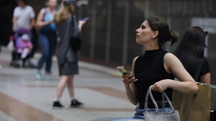 A beautiful brunette is waiting for the train to arrive at the metro station.