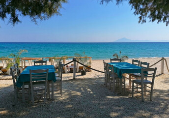 Beach restaurant on the island of Thasos, Greece stock photo images. Tables and chairs on the beach of Thassos, Greece. Beautiful beach in Limenaria resort photo images