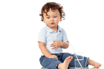 Cute curly haired toddler drinking water form a straw and having fun with a smile