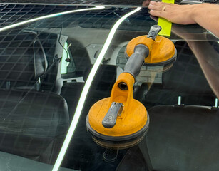Automobile special workers replacing windscreen or windshield of a car in auto service station garage. Glass of the car, removed with the help of professional suction cups. The process of car repair. 