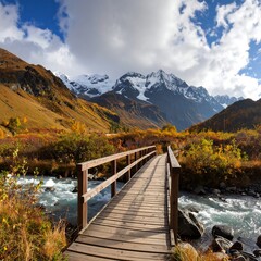 Obraz premium Wooden footbridge over a mountain stream, autumn foliage and snow-capped peaks in the background (1)