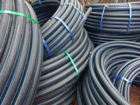 Pile of coiled black MDPE water pipe for plumbing systems