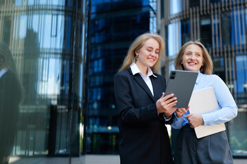 Two professionals sharing a moment of joy while discussing plans outside a modern office building in the city