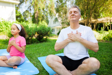 Mindful moments of connection between a child and her father in serene outdoor yoga practice
