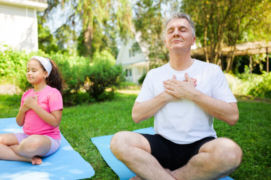 Mindful moments of connection between a child and her father in serene outdoor yoga practice