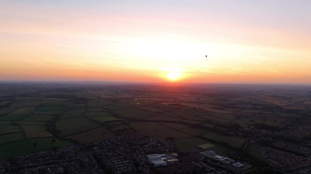 Aerial drone view of paraglider recreational sport flying at sunset over small English town Oakham Rutland rural landscapes UK 