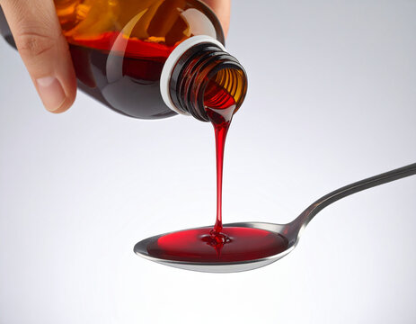 Pouring Red Syrup from Bottle into Spoon on White Background. - Powered by Adobe