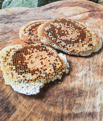 Fresh natural honeycomb sections with hexagonal cells containing honey and bee larvae on rustic wooden surface