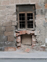 This weathered stone wall features an old wooden window, hinting at years of history. The rough texture and faded colors tell stories of time. Can be used as elements for design projects. 
