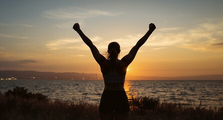 Fototapeta premium Silhouette of Woman with Raised Arms at Sunset by the Water