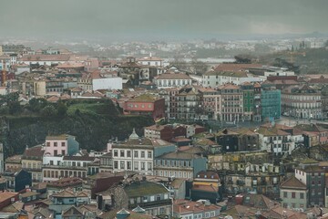 A panoramic view unfolds, showcasing aged structures and quaint streets under a heavy, grey sky, as rooftops spread towards the distant horizon in Vila Nova de Gaia