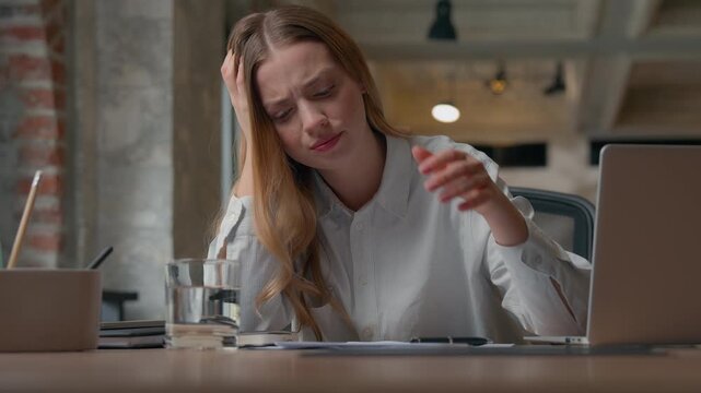 Stressed overworked Caucasian business woman holding head pensive suffering boring job in office employer girl female businesswoman at table typing laptop writing notes incorrect data solving trouble