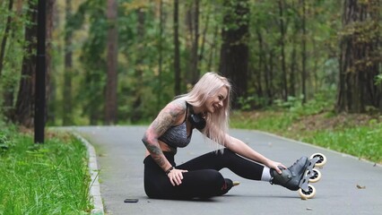 Attractive blonde relaxes while roller skating. She sits on the bike path and poses for the camera....