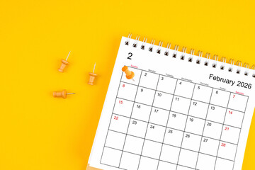February 2026 Monthly desk calendar for 2026 year with wooden pin on yellow background.